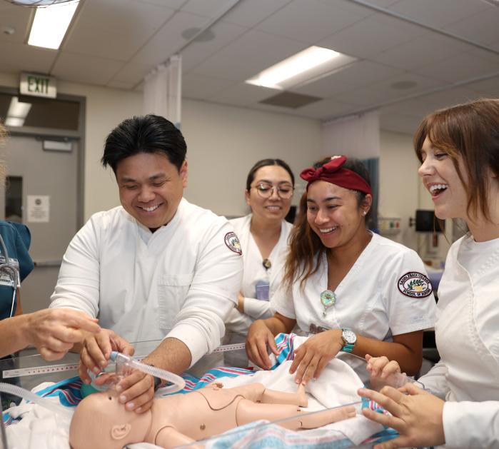 Students working on an infant medical dummy in a lab.
