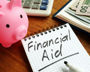 Image of a notepad with the works Financial Aid written on it. A piggy bank, a calculator, and a few $50 bills are also seen in the image.