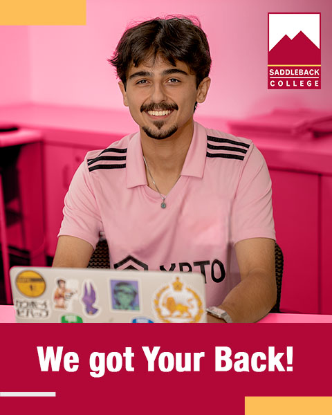 Male student working at their laptop smiling at the camera. We got your Back!