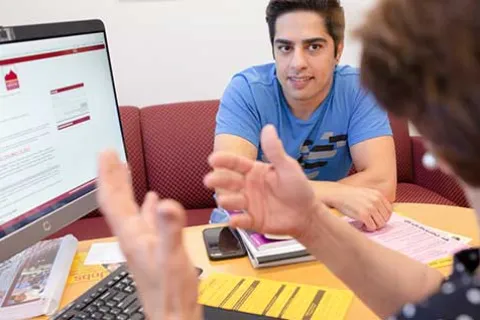 Student Support: Man in counselor office looking at computer screen.