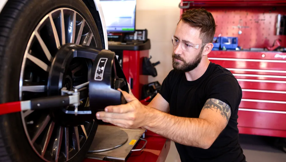 Student fixing a wheel on a car.