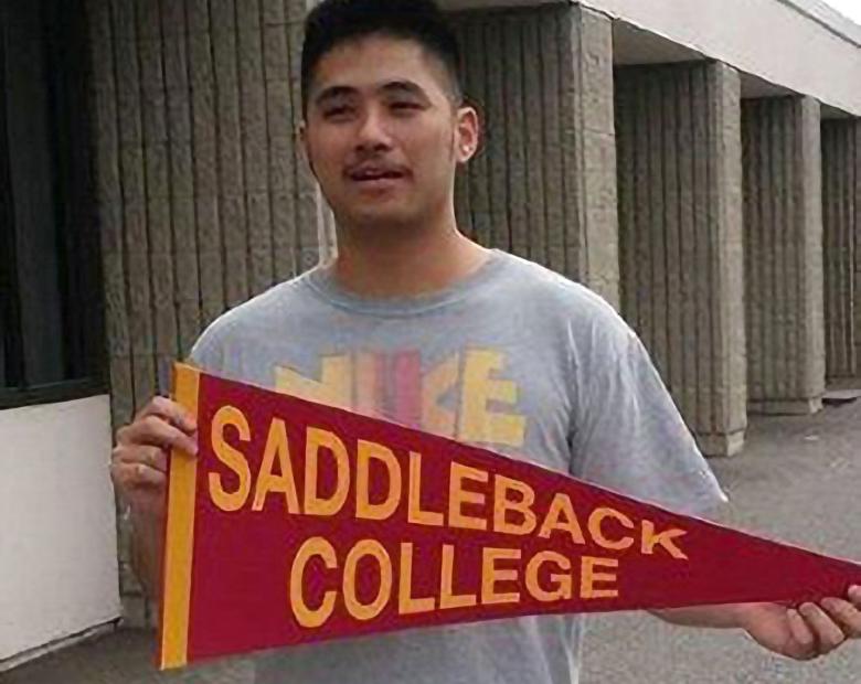 International student holding a Saddleback College pennant