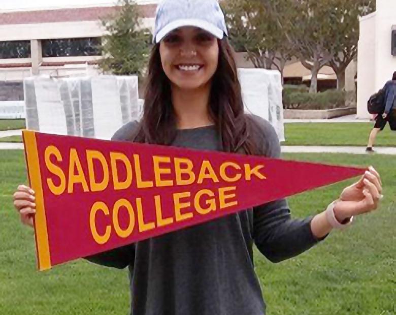 International student holding a Saddleback College pennant
