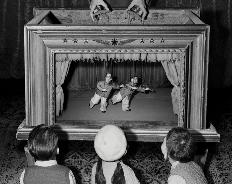 Black and white photo of children watching a puppet show.