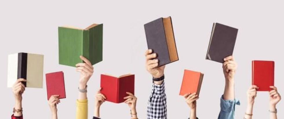 A group of hands holding up books.
