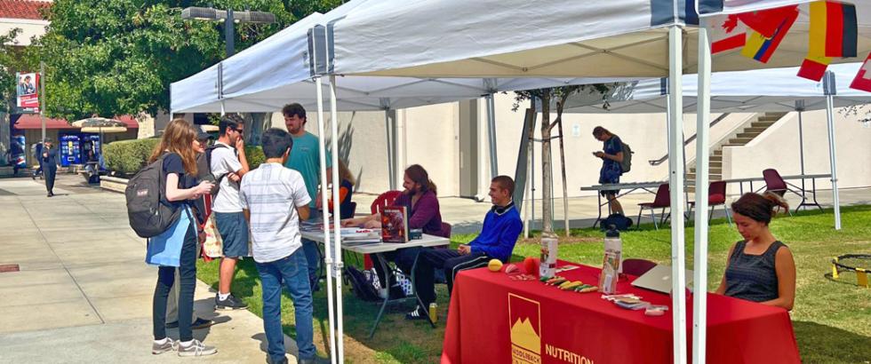 Students gathered around a table speaking to other students