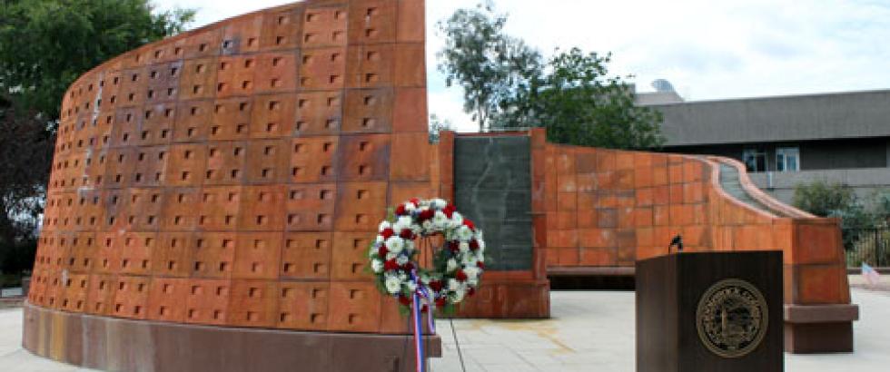 The Saddleback Veterans Memorial is pictured in the background and a wreath with red and white flowers is on display in the foreground