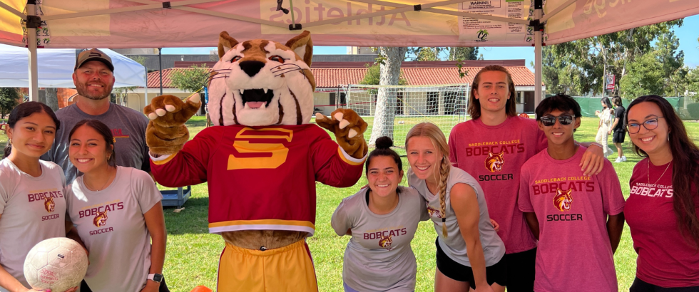 Student athletes posing with the cheerful Bobcat mascot.