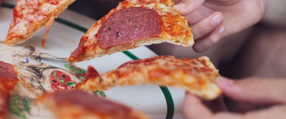 Slices of pizza in hands of a group of people