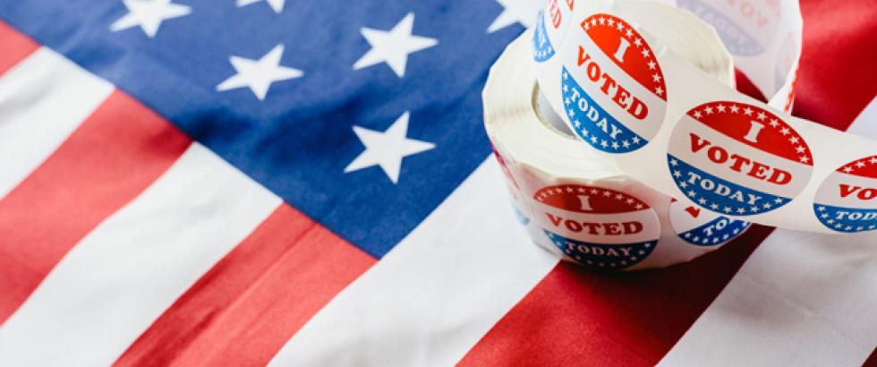 Image of a roll of I Voted Stickers resting on an American flag.