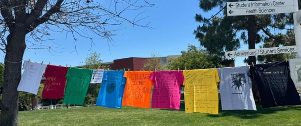 Image of shirts featuring testimonials from sexual assault survivors hung from a clothesline as part of the Clothesline Project.