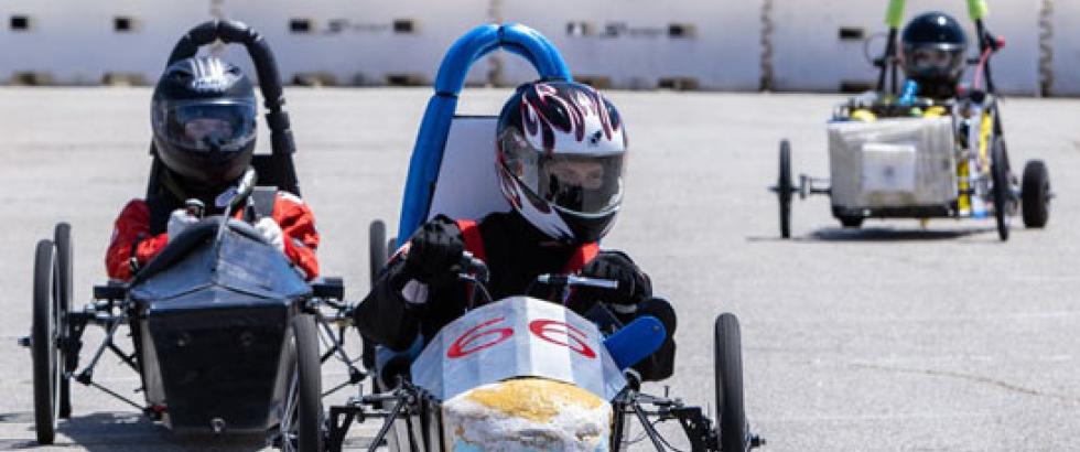 Three racers navigate a course in their electric vehicles. 