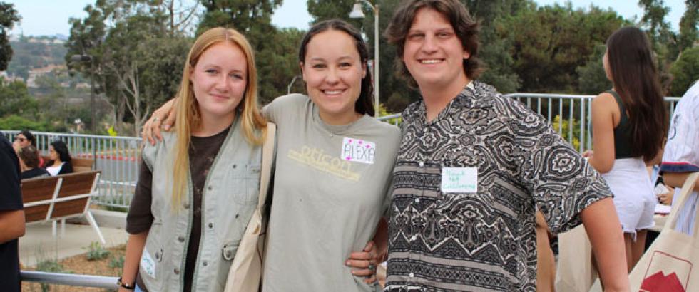Three students standing together and smiling at the camera