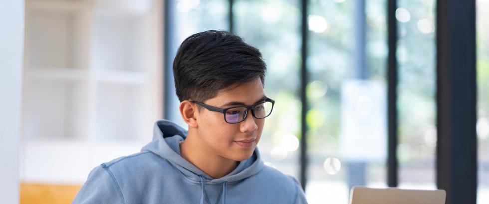 Young collage student using computer and mobile device studying online.