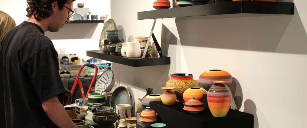 male looking at handmade ceramics and other art pieces