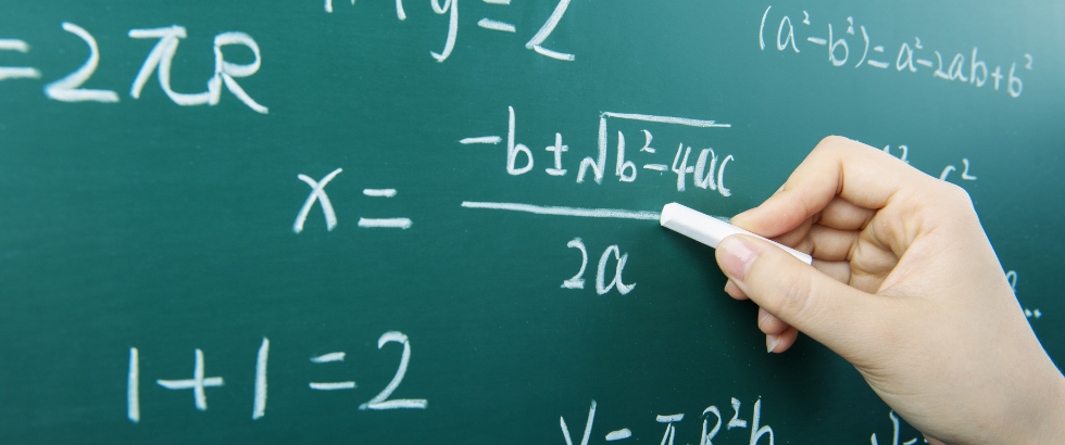 hand solving math problems in white chalk on a green chalkboard