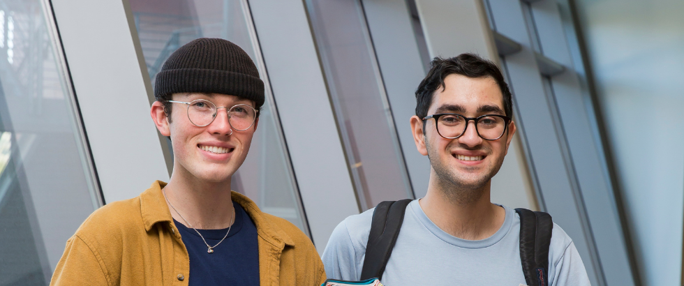 two students standing in front of a window