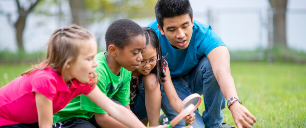 adult child care employee outside with various children looking at bugs