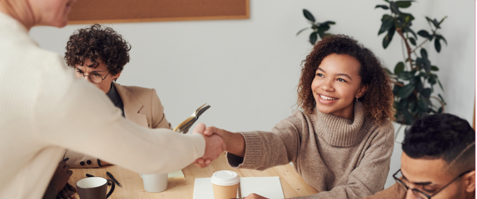 young woman shaking hands with someone you cannot see 