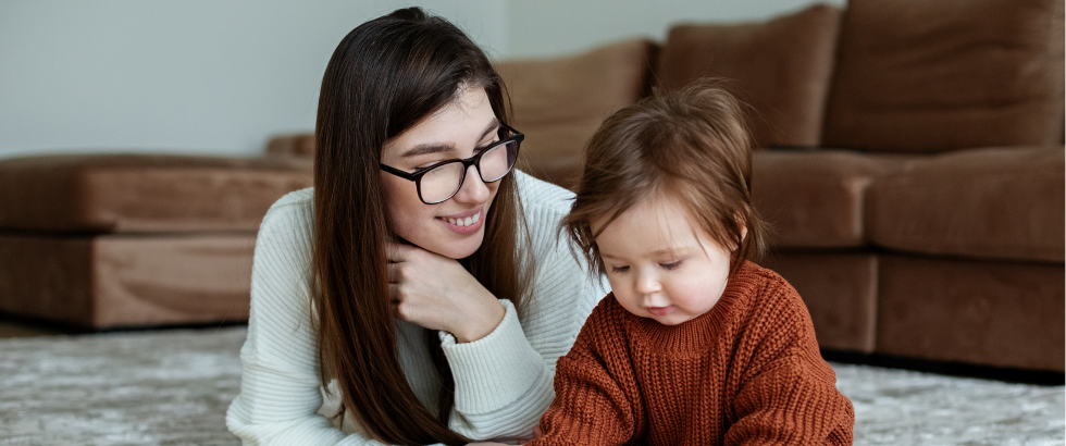 woman and small child play educational games on rug.