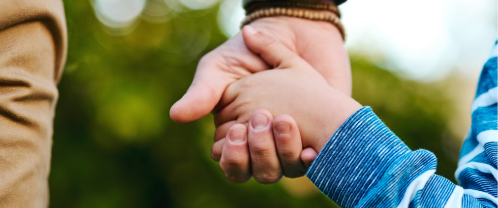 cropped shot of a little boy holding on to an adult hand