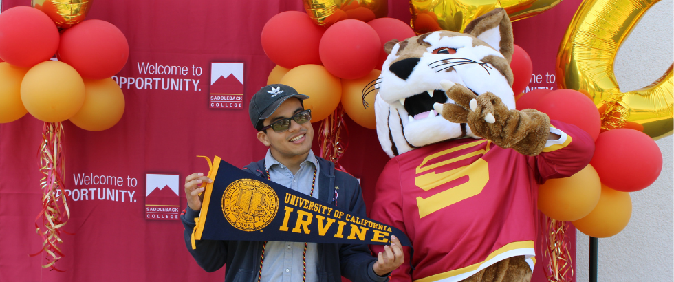 Mascot and student holding UC Irvine pennant.