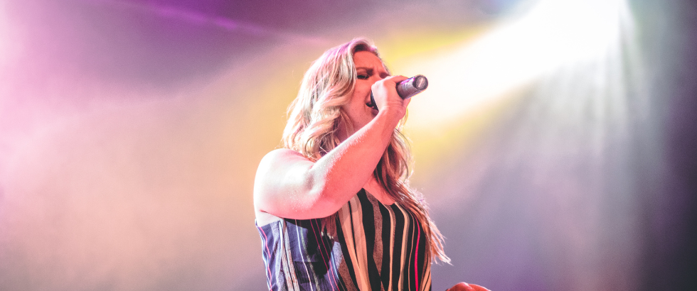 woman wearing black and white stiped top singing on stage