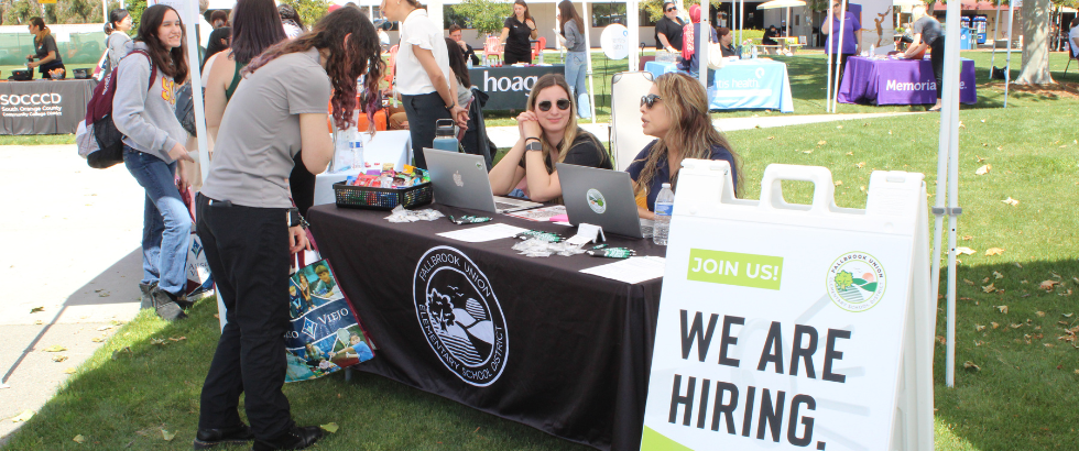 students visiting various employer booths outdoors