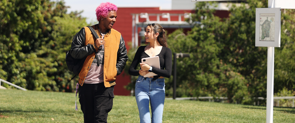 two students walking across the lawn talking