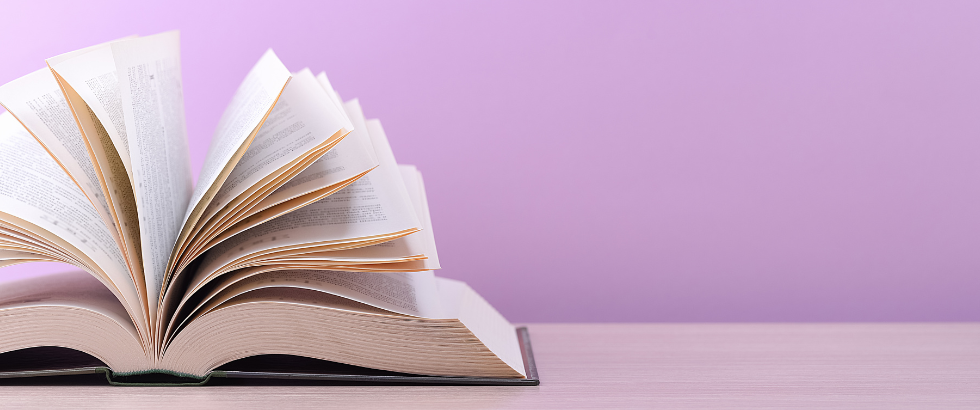 a large, thick hardcover book lies open on a light-wood table.