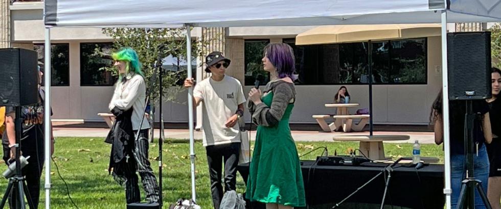 Student in a green dress holding a microphone and preparing to sing karaoke