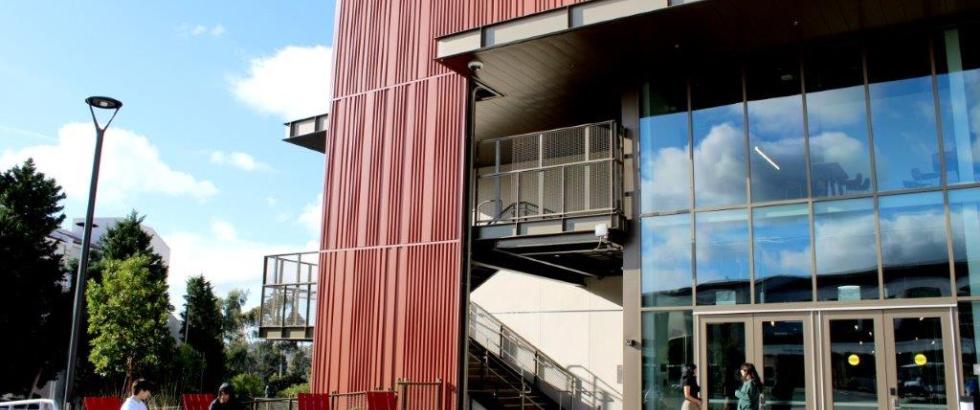 The Gateway building is pictured with students sitting in red chairs in front of it.