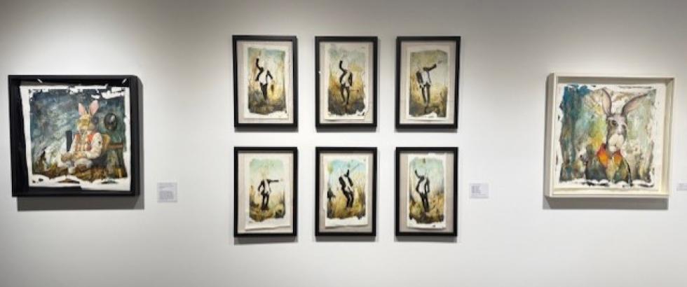 the image includes several framed pieces of art from an exhibition in the art gallery