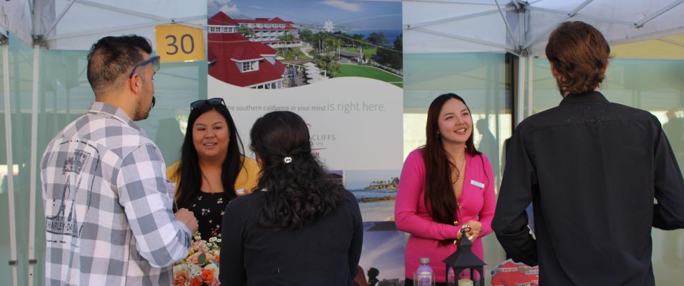 Two employers speak to students at their company's booth during the Job and Internship Fair
