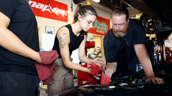 Auto motive student and teacher looking into a car engine.