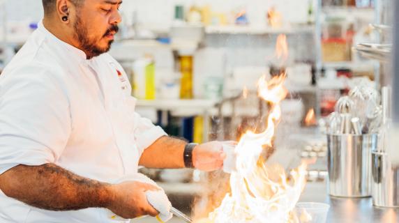ATEP Culinary student cooking with flaming pan.