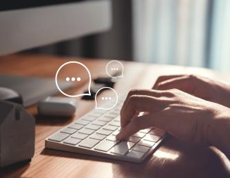 Hands typing on a keyboard with word bubbles appearing