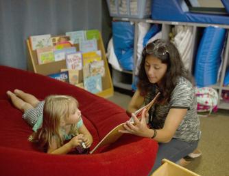 Child Development Aide reading a book to a child in Saddleback's CDC