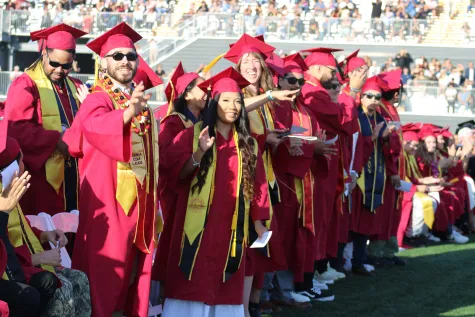 A group of military veteran graduates stand during the commencement ceremony to be recognized for their military service.