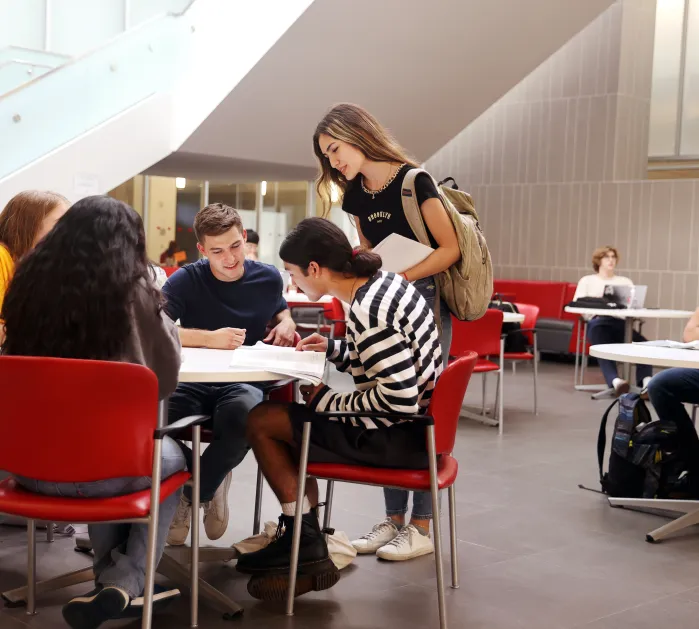 Saddleback College students sitting around a table looking at a book