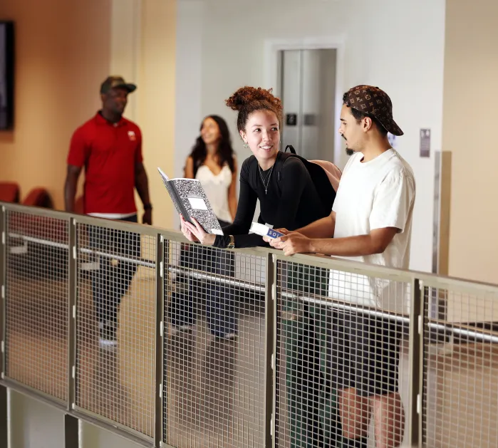 Students talking leaning against railing.