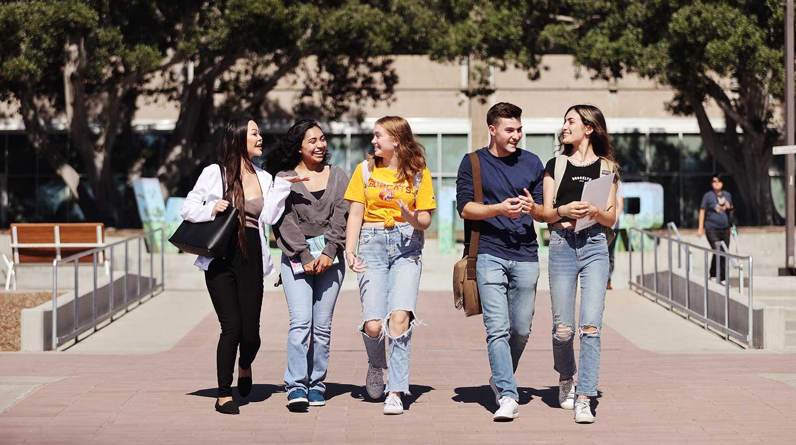 Group of Saddleback College students in conversation walking toward camera.