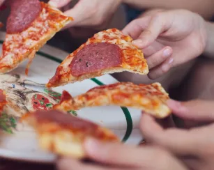 Slices of pizza in hands of a group of people