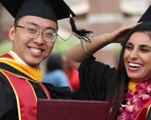 male and female in graduation cap and gown, holding diploma