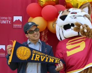 Mascot and student holding UC Irvine pennant.