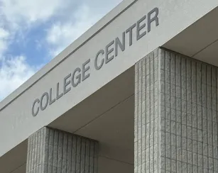 photo of the college center building against a blue sky, the words college center are on the stucco in a dark grey
