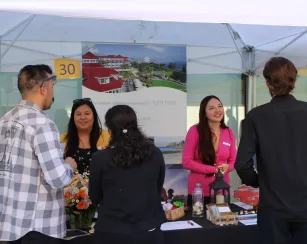 Two employers speak to students at their company's booth during the Job and Internship Fair