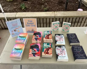 A table at Saddleback College displays free books celebrating Asian American, Native Hawaiian, and Pacific Islander Heritage Month, with titles including Fairest, The Good Immigrant, Dear Girls, No-No Boy, All You Can Ever Know, and Island Wisdom.