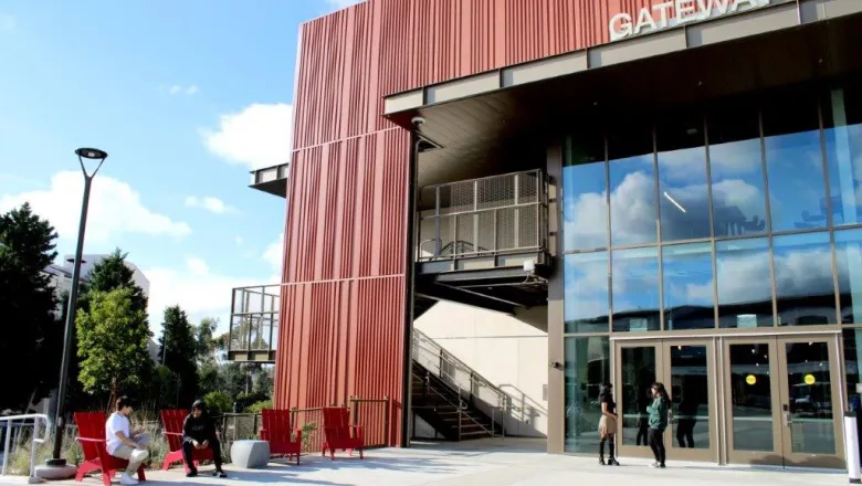The Gateway building is pictured with students sitting in red chairs in front of it.