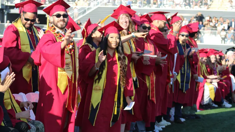 A group of military veteran graduates stand during the commencement ceremony to be recognized for their military service.